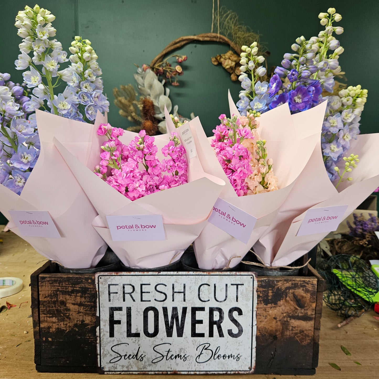 Bouquets of flowers with a 'Fresh Cut Flowers' sign in the background | Locally Grown Flowers | Bunches Stock | Bunched Delphinium