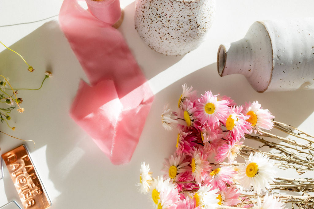 Ceramic bud vases and dried pink and white paper daisies 