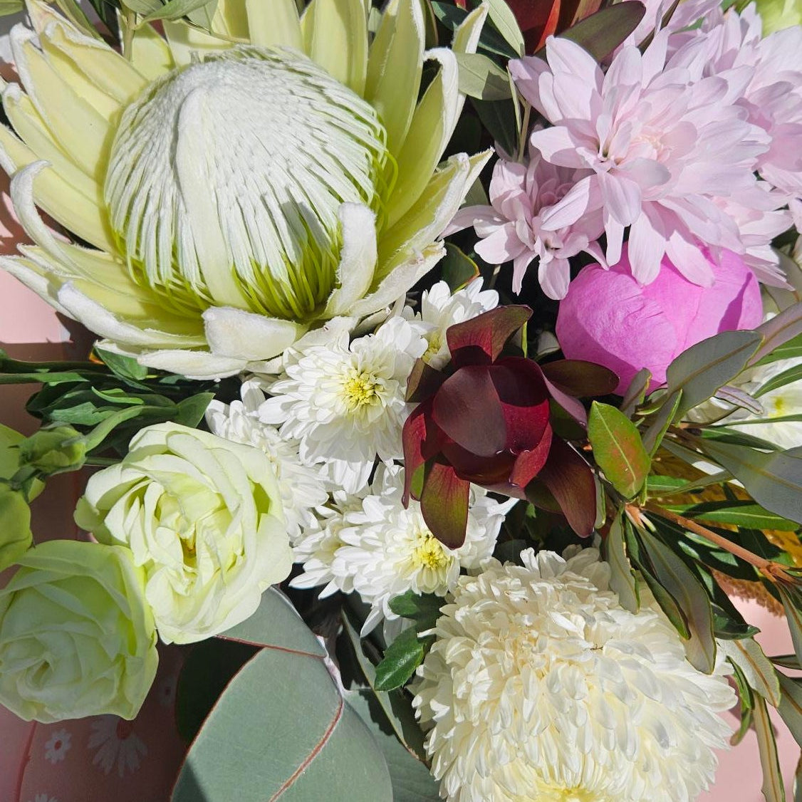 Bouquet of flowers with greenery on a pink surface
