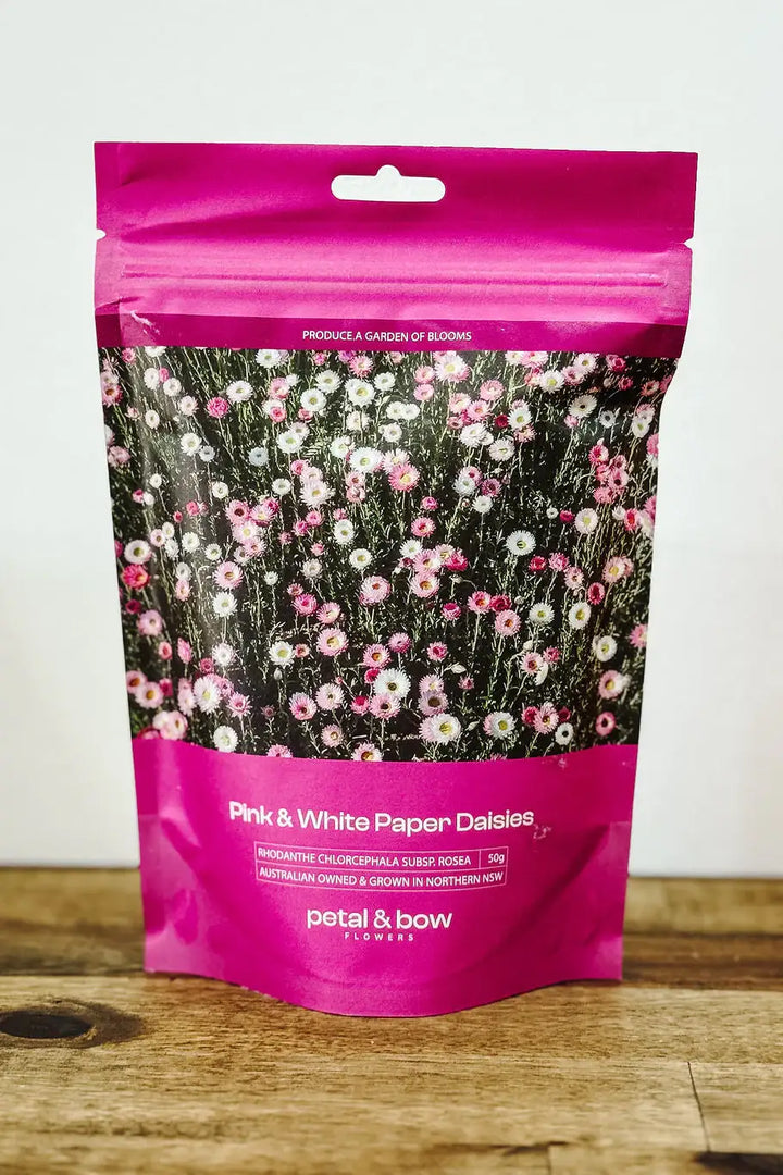 Petal and bow flowers Pink and white paper daisies packaging on a wooden surface