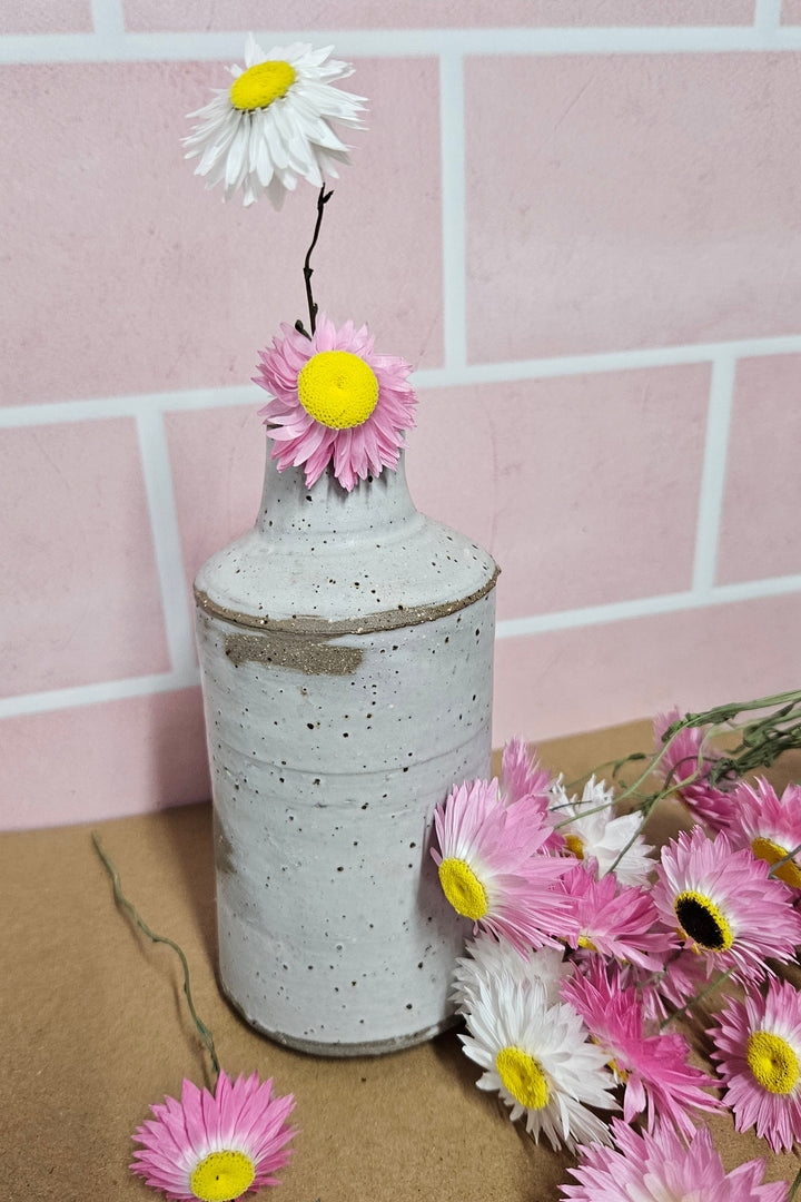 Decorative vase with dried paper daisies in pink and white. 