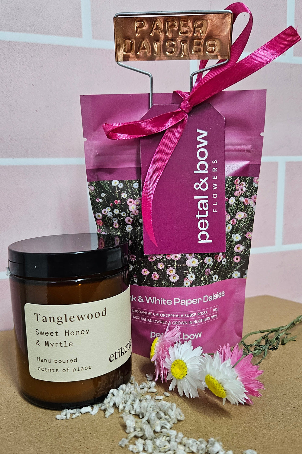 A candle, copper tag and packet of paper daisy seeds