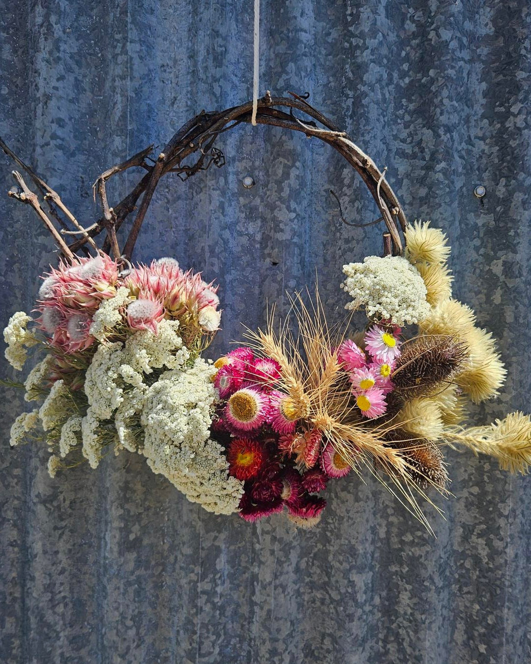Floral wreath with pink and white flowers against a corrugated metal background